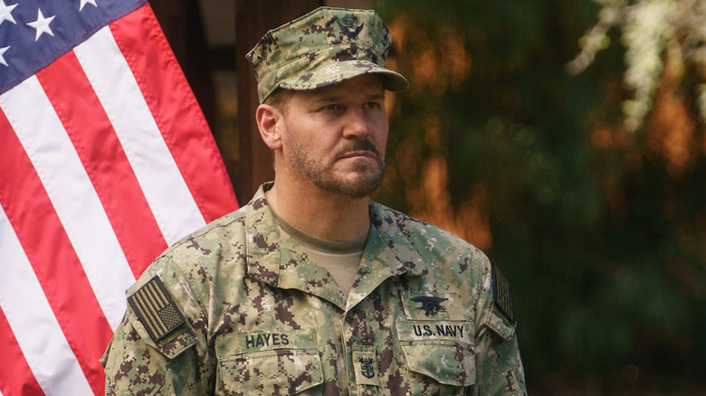 Jason (David Boreanaz) standing in front of an American flag on "SEAL Team."