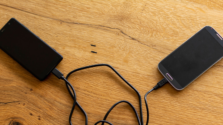 Two Android phones connected to each other with a USB cable on a table