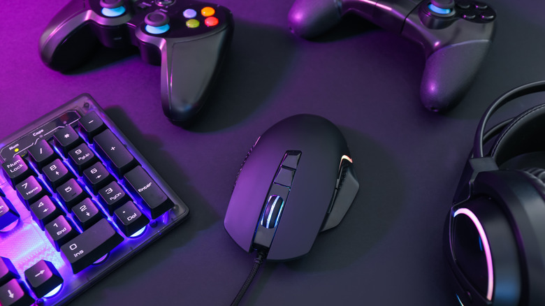 A pair of game controllers, headphones, keyboard, and mouse on a desk