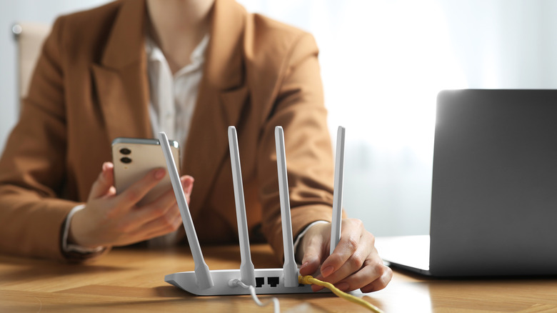 A person connecting an Ethernet cable in a router to use with a smartphone