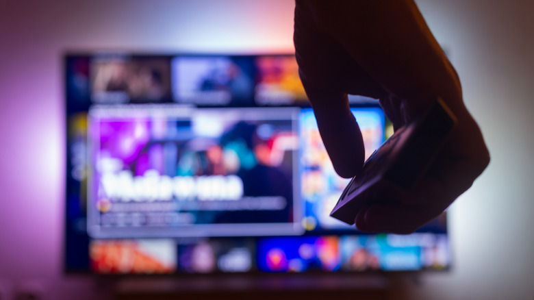 A hand pointing a remote at a smart TV