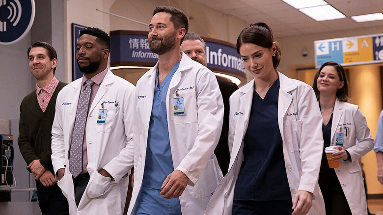 Doctors and other staff walk down a hospital hallway smiling in New Amsterdam.
