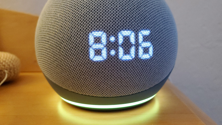 An Amazon Echo Dot displaying the time on a side table