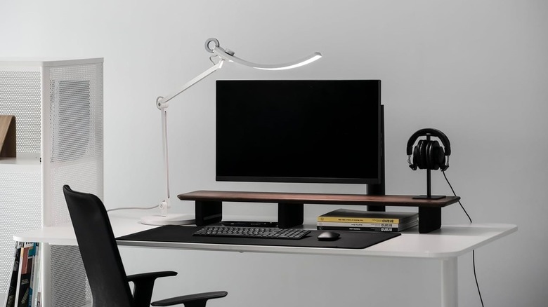 BenQ e-Reading desk lamp on office desk with monitor, headphones, and more in view.