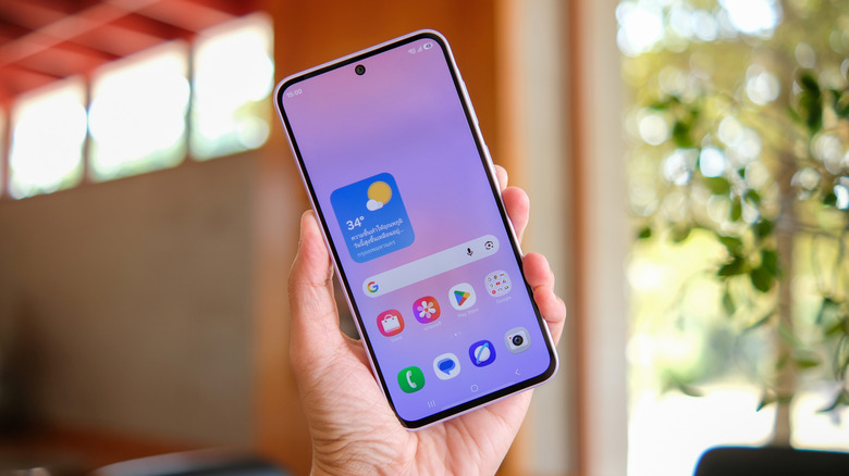 Samsung Galaxy A37 held in hand, showing its front display and home screen.