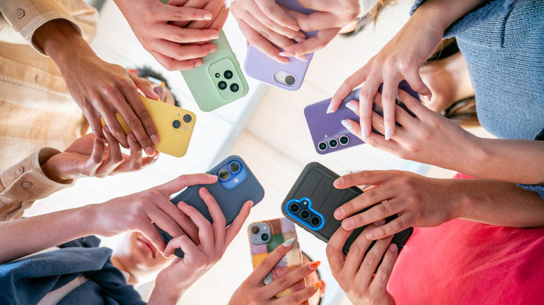 A group of people holding colorful smartphones in a circle.
