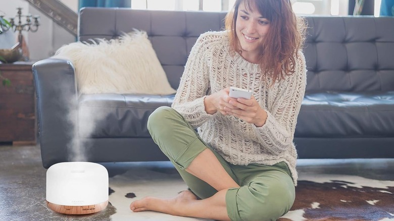 A person controlling Asakuki Smart Wi-Fi Essential Oil Diffuser with their smartphone