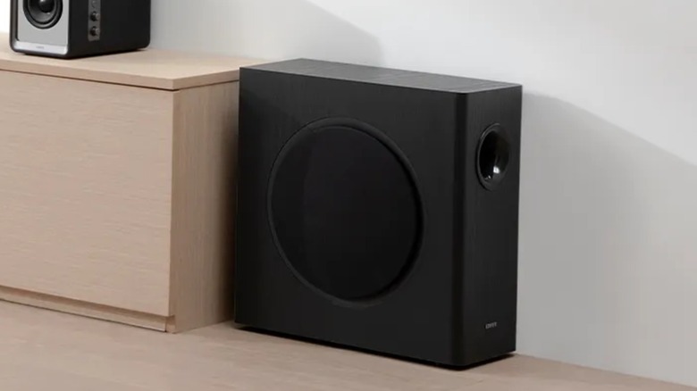 A black Edifier TS5 subwoofer sits on the floor next to a counter
