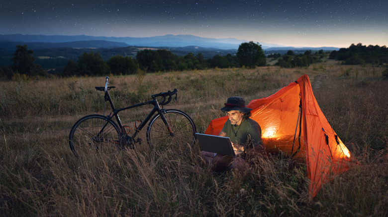Sitting in a field with a tent, bike, and laptop