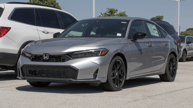 A Honda Civic with a hatchback, displayed outdoors at a dealer lot.