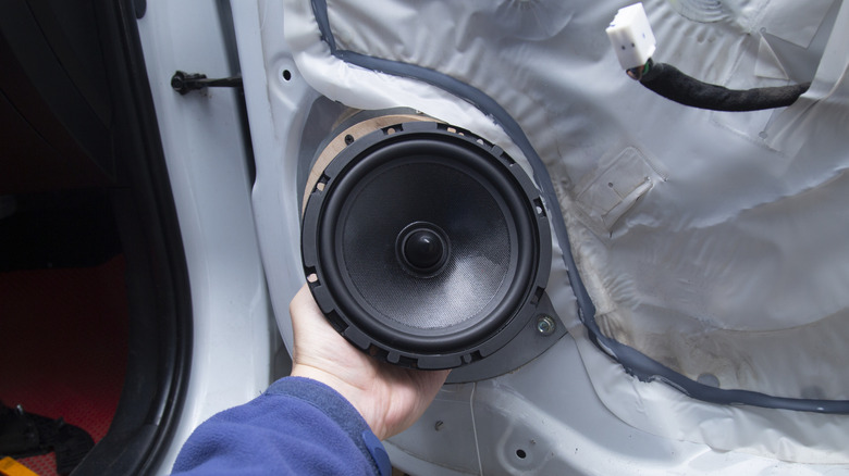 A car door speaker being installed by an engineer.
