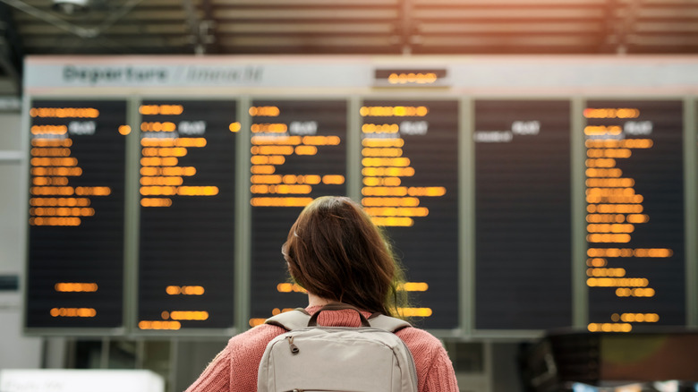 woman looking at departures board at an airport