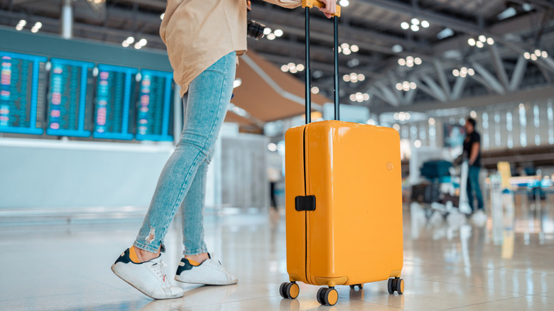 person at airport with a carry-on suitcase