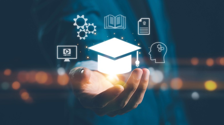 a hand with a digital image of a graduation cap and other education icons