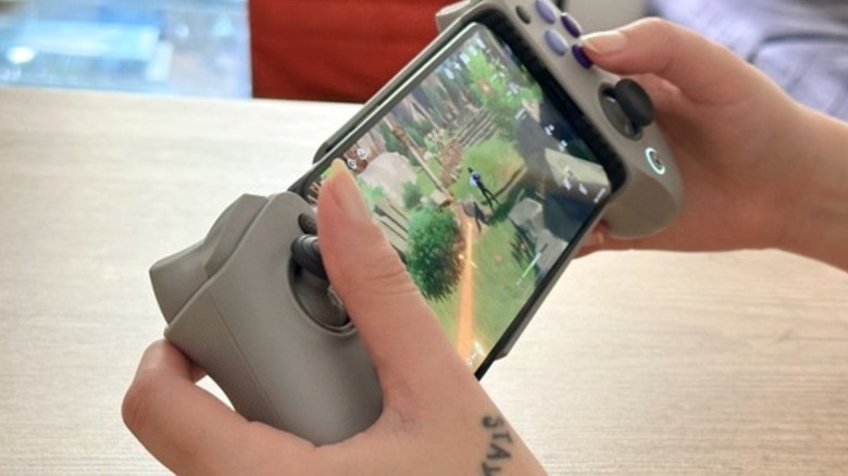 Woman playing Genshin impact with a gaming controller on an iPhone