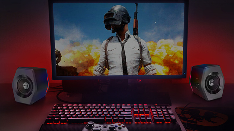 Edifier G2000 on either side of a monitor with key art from the game PUBG on the screen