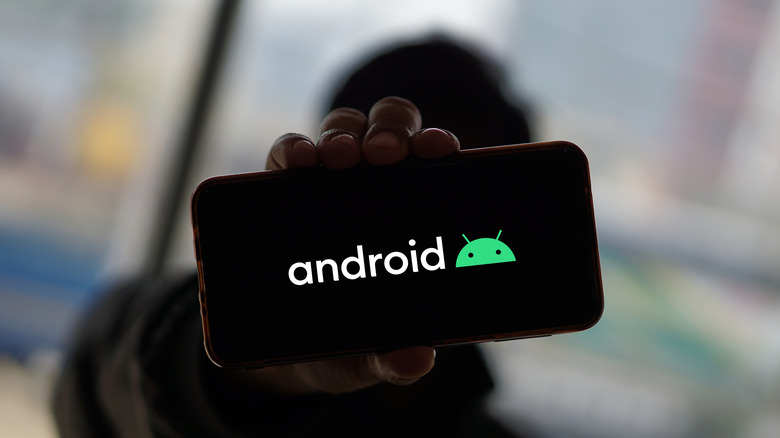Person holding a phone displaying the Android logo.