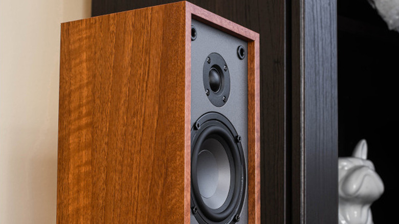 The Dayton Audio B65 Bookshelf speaker on a stand in a living room