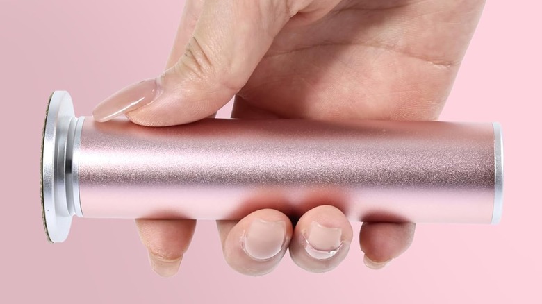 The Aprelm Electric Foot Callus Remover held horizontally in an individual's right hand