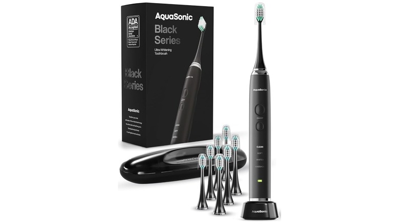 Amazon promotional image showcasing the Aquasonic Black Series Ultra Whitening Toothbrush, the image features the toothbrush, charging station, additional heads, and packaging against a white background