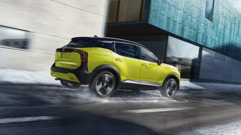 2026 Nissan Kicks driving on a wet road in rainy conditions.