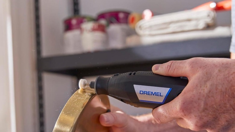 A hand using a dremel polishing tool on a class impression of a basketball
