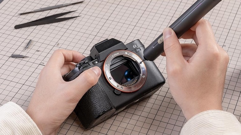 Hands using the Fanttik electric screwdriver on a Sony Alpha camera