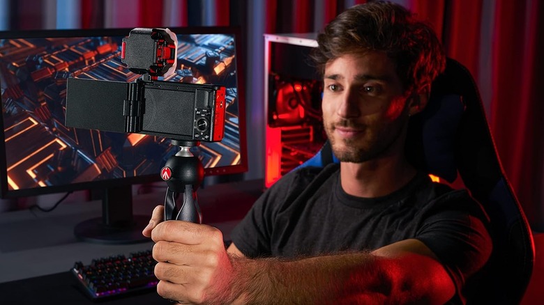 A man sitting in front of a gaming computer using the Manfrotto tripod with his camera
