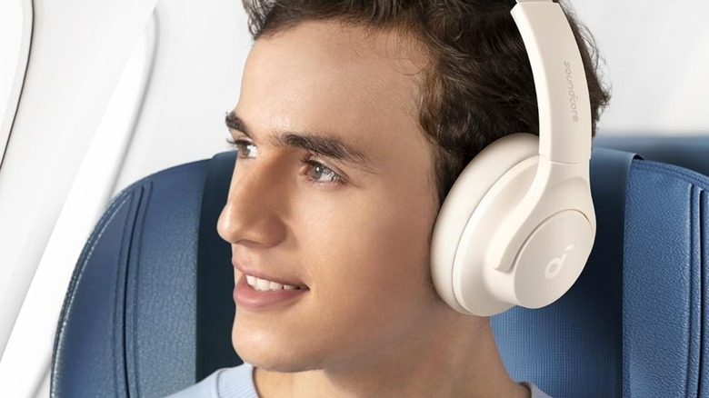 Person wearing white Soundcore by Anker Q20i in airplane