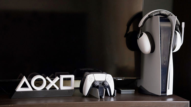 A PlayStation 5 on display with a pair of headphones and a DualSense controller.