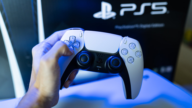 A person holding a PS5 DualSense controller.