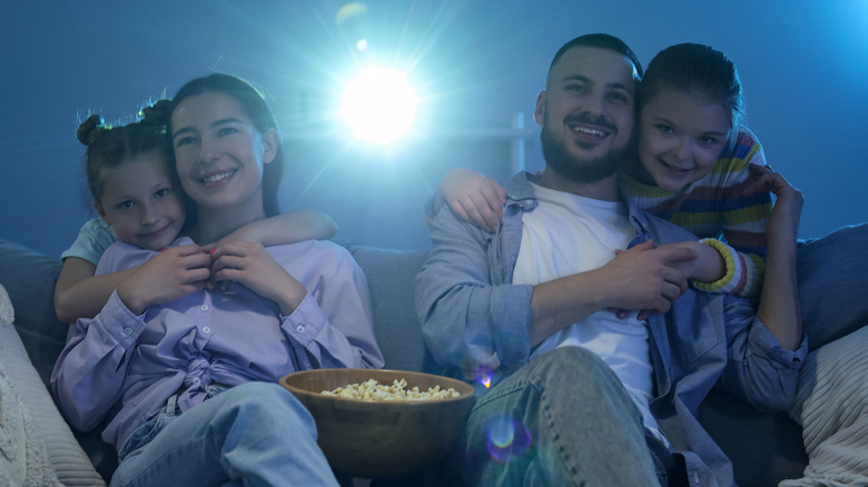 A family using a projector for movie night in what looks like an indoor setting.