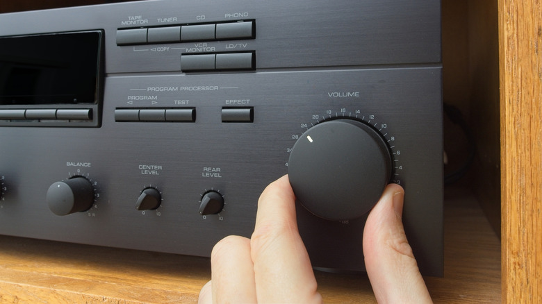 A hand turning a volume knob on a music amplifier