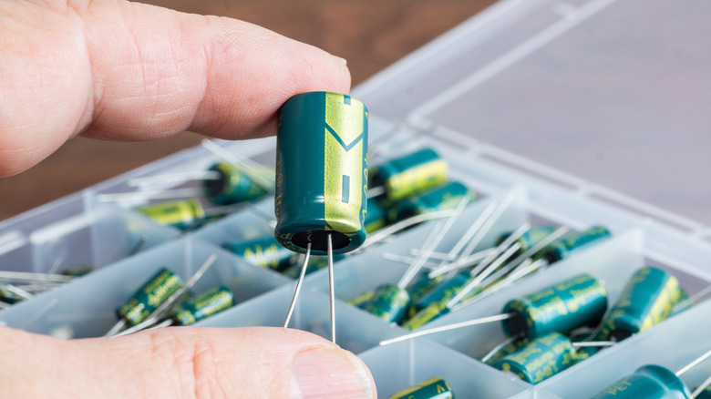 Person holding a green capacitor