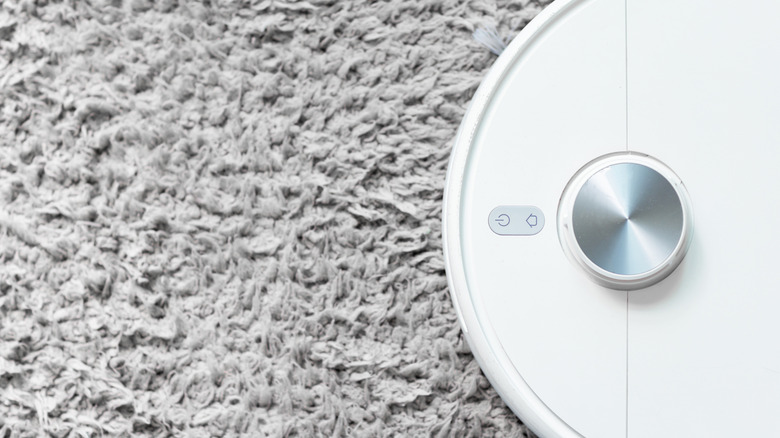 A robot vacuum faces toward a section of carpeting.