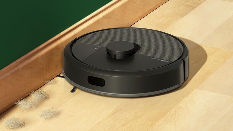 The iRobot Roomba 105 cleaning dust bunnies along some base trim.