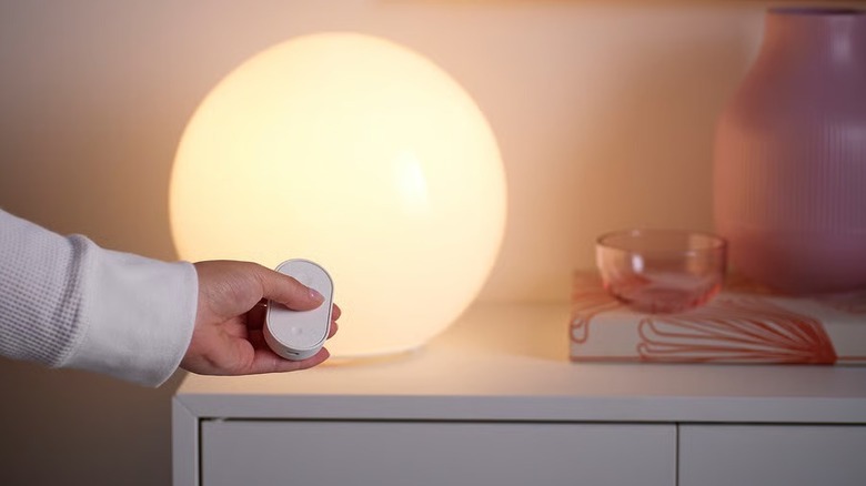 Hand using Ikea Bilresa Smart Remote Control to control lights