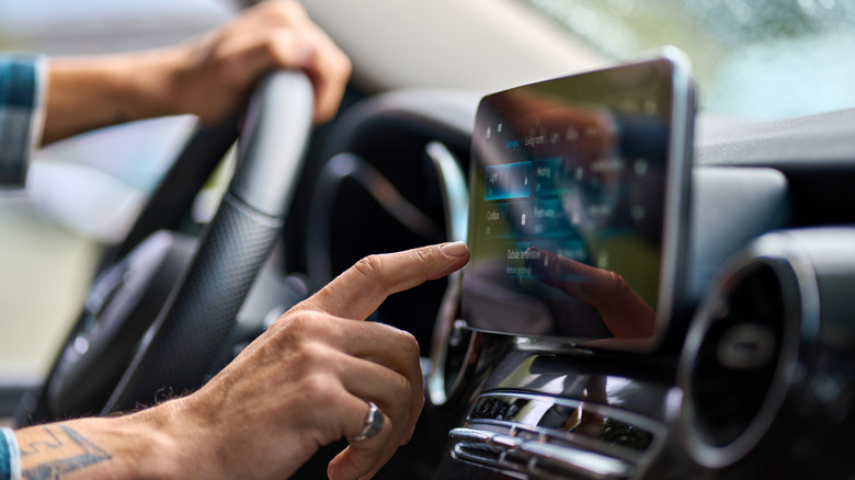 Driver interacting with in-vehicle display and using modern tech.