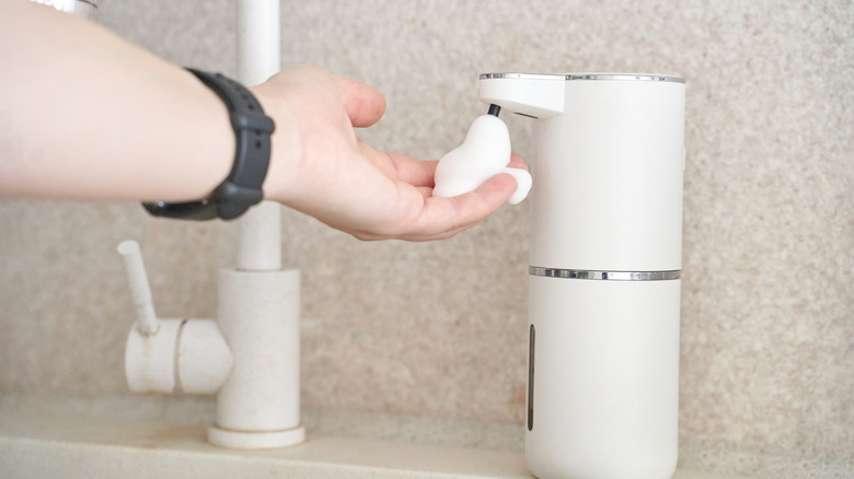 Hand under touchless soap dispenser