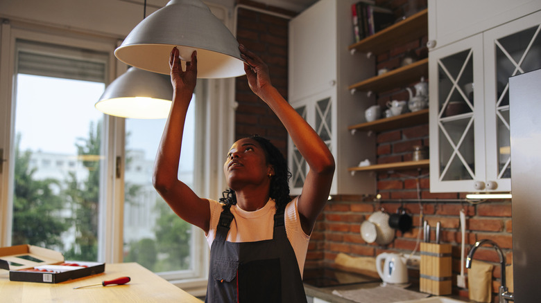 Homeowner changing lightbulb in kitchen