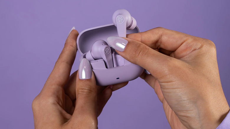 Hands holding a purple pair of JLab Go Pods ANC earbuds.