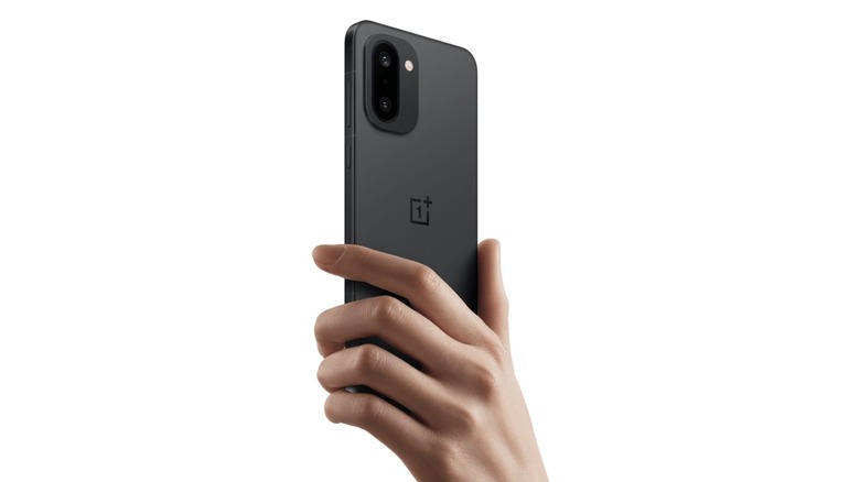 Hand holding a black OnePlus 15R with the rear cameras visible.