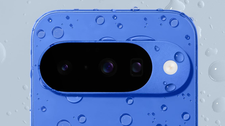 Close-up of a blue Google Pixel 10 with water droplets on the rear camera bar.