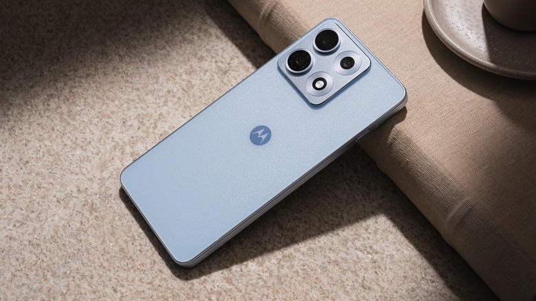 The Motorola Edge 70 Max face down on table with its top resting on a book's spine