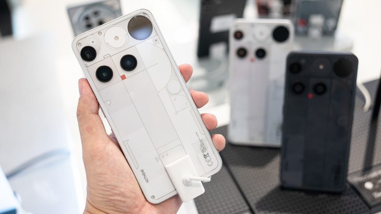 Nothing Phone (3) in white held upright in a hand, showing its Glyph Matrix and cameras.