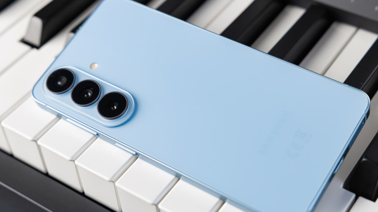 Samsung Galaxy S26 in light blue color lying face down on a piano.
