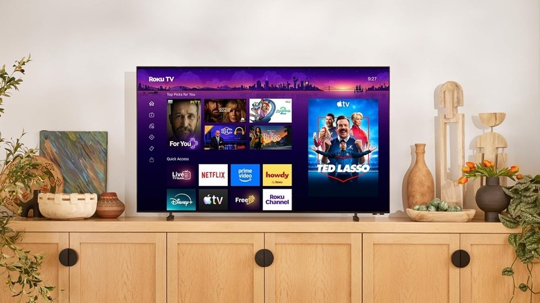 Roku Pro Series OLED TV on a wooden multimedia unit surrounded by decorations