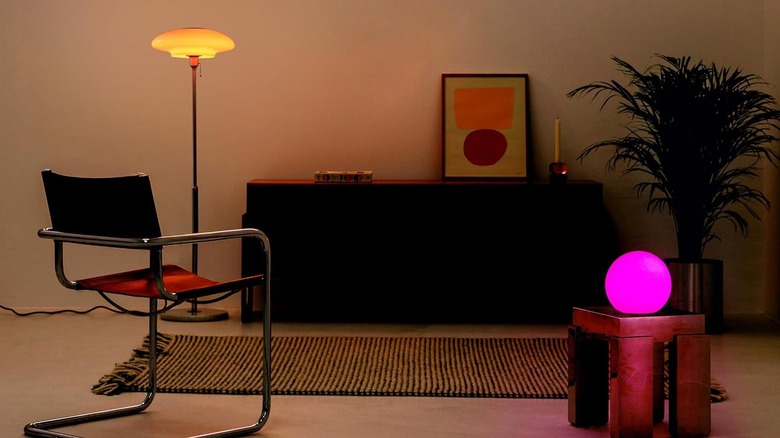 LIFX Smart Light Bulbs being used in a living room setting. One is screwed into a floor lamp, while the other is screwed into a globe-shaped lamp on an end table.