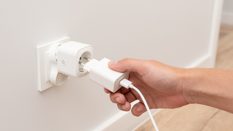 close-up of a person plugging something into smart plug