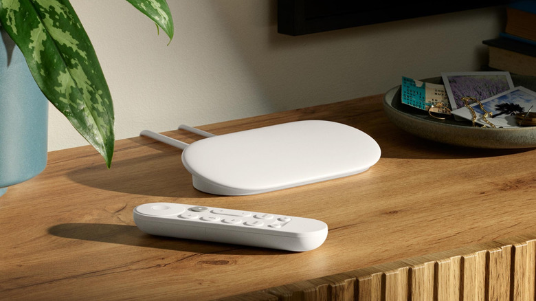Google TV Streamer and remote resting on a wooden media console.
